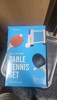 Box showing front product image and contents: paddles, balls, retractable net, carrying case