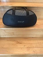 Front view of the Five S carrying case showing black leather-like material with quilted gray fabric and logo