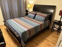 Photo showing assembled queen size dark wood sleigh bed frame with headboard, footboard, and side rails in bedroom