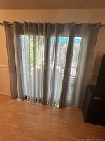 Four linen blend curtain panels hung on a curtain rod, showing the light taupe color with vertical cream stripes, covering a patio door.