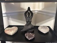 Photo showing Black Madonna statue seated in yoga pose with three different heart-shaped decorative stones