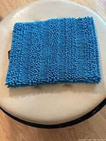 Flat view of blue fluffy bath mat showing texture and fabric detail.