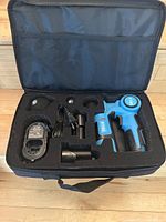 Photo of the Vybe muscle massage gun and accessories organized inside a black zippered carry case with foam padding.