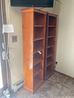 Pair of tall wooden bookcases next to each other in a room, showing overall appearance and size.