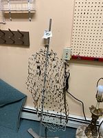 Full view of antique wire mesh metal dress form mounted on metal stand, showing hooks and overall shape.