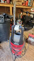 Front view of red and black Husky power washer showing the model number, handle, and attached hose and wand.