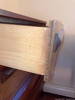 Close-up side view of one wooden drawer showing dovetail joinery and geometric wood handle.