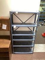 Full view of gray metal shelving unit with five shelves, showing structure and condition.