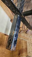 Close-up photo showing rust and wear on black painted metal hitch attachment point with a mounting hole.