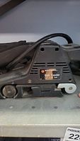 Black and Decker belt sander with power cord visible, showing identification label.