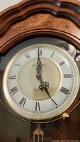 Close-up of clock face with Roman numerals and decorative black hands within a gold-tone bezel, showing the Westminster Quartz labeling.
