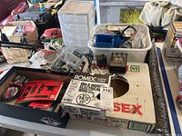 Table with electrical wire spools, boxes and bins of mixed electrical and plumbing parts.