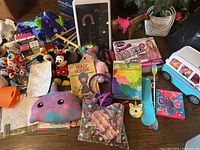 Photo showing a variety of girls toys including plush animals, doll accessories, crafting kits, toy tent, and books.
