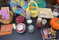 Overview of holiday decorations including pastel Easter basket, orange pumpkin container, candles, glittery purple letter decorations, and bowls with autumn designs.