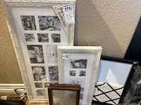 Three photo frames leaning against a wall: one large white collage frame, one medium white collage frame, one small wooden frame; all new in original packaging except small wooden frame.