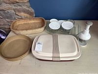 Wide view of the collection showing stoneware baking dishes, a covered stoneware dish, and a white kitchen tool