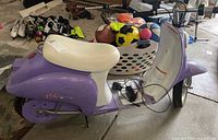 Side view of purple Razor electric kids scooter showing white seat, large plastic body, butterfly decorations, and charger cord on the footrest.