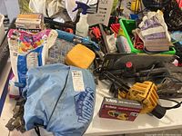 Overview of assorted hand tools, cleaning supplies, gloves, blue Denver Nuggets bag, and grout-related items on table.