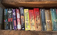 Books on a wooden shelf showing multiple titles by Stephen King, Stieg Larsson, and other authors