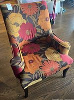 Front and angle views of upholstered arm chair with floral pattern fabric, showing the design and structure.
