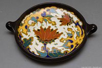Top view showing detailed colorful hand-painted interior pattern with yellow, brown, blue, green, and white motifs and two brown handles.