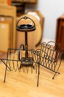 Photo showing the brass ashtray floor stand with glass ashtray and two wrought iron magazine racks from a distance.