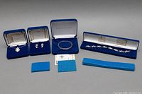 Full view of all jewelry pieces in their original blue presentation boxes along with foam inserts.