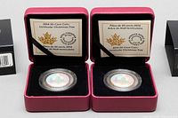 Two 2014 Royal Canadian Mint 50-cent lenticular Christmas tree coins in open maroon presentation boxes with certificates on display.
