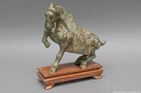 Front angle view of the bronze Chinese Tang style horse statue on wooden base showing detailed patina and intricate saddle design.