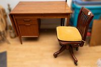 Full view of teak desk and matching wooden office chair with upholstered seat, showing overall appearance and condition