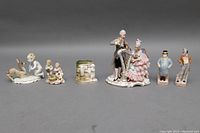Full view of the eight porcelain figurines including couple playing harp and violin, children figures, and animal figures