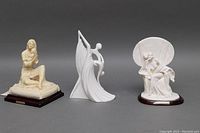 Full view of three vintage A. Santini sculptures showing their size difference, material, poses, and wooden bases with plaques.