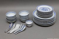 Full set showing various plates, bowls, saki cup and spoons arranged.