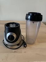 Photo of blender motor base with control dial and clear jar to the right on wooden surface.