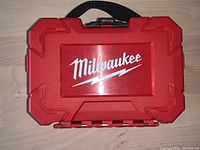Closed red plastic Milwaukee case with the Milwaukee logo embossed on the top.