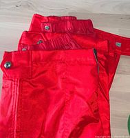 Red Descente men's ski pants showing waist and leg with button closures and fabric texture.