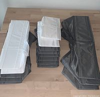 Photo showing four white and four gray Ikea Skubb fabric storage organizers stacked on a wooden surface.