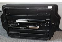 Underside view of the raising table showing the adjustable height mechanism with metal rods and cylinders.