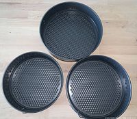 Three round textured-bottom non-stick springform pans, showing top view of pan interiors.