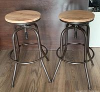 Pair of two adjustable height wooden-top bar stools with industrial style metal frames