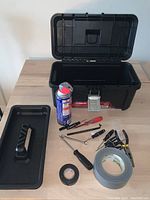 Open toolbox with tools and accessories laid out on its lid and surface