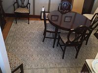 Full room view showing the grey area rug under a wooden dining table and chairs, highlighting the overall size and pattern of the rug.