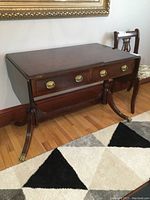 Angle view of the desk showing top surface with drop leaves down and drawer fronts.