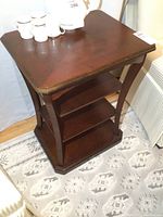 Full angled view showing shape, shelves, and wood finish of the Bombay display table.