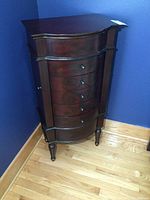 Front view showing curved front, six drawers, decorative motifs and metal knobs