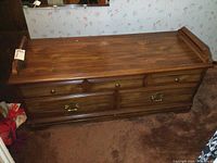 Full view of the wooden cedar lined chest bench with four drawers and a shaped backrest edge on the top sides. Exhibits scratches on the top surface.
