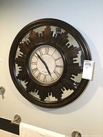 Full front view of large resin sunburst style wall clock with mirrored back and Roman numeral clock face