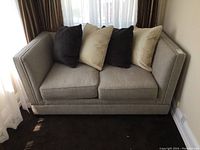 Front-facing view of grey loveseat with four throw pillows