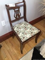 Front and angle views of the wooden lyre back chair showing floral upholstered cushioned seat and decorative back splat.