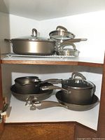 Full view of the shelf with various Circulon pots, pans, and lids stacked.